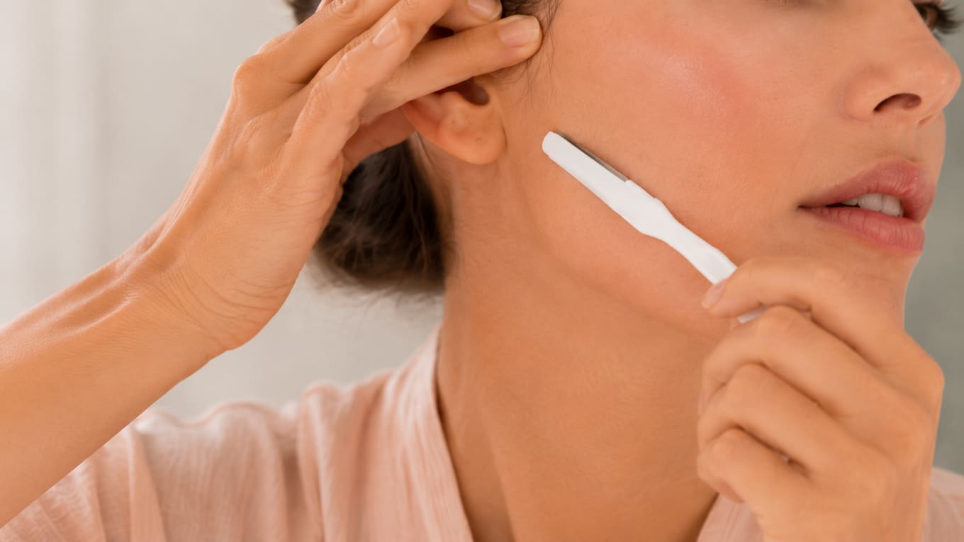 Holding the skin taut and sweeping the dermaplaning blade at a 45-degree angle along the cheek