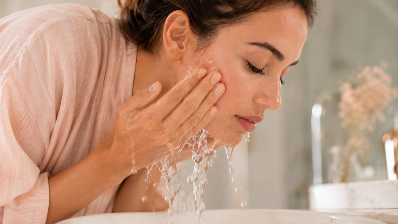 Rinsing the face with cool water at the sink